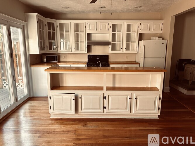 A kitchen with white cabinets and a wooden floor.