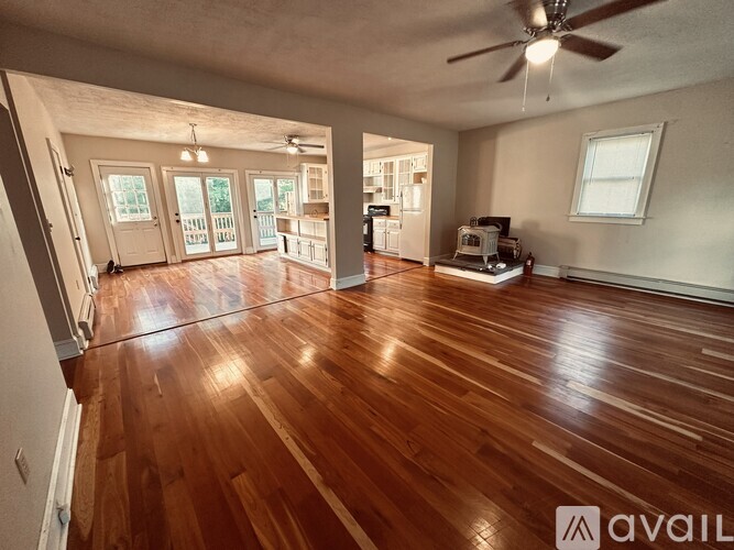 A spacious room with wooden floors and a ceiling fan.