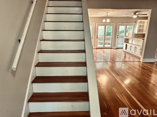 A wooden staircase with white risers leads to a bright open living area.