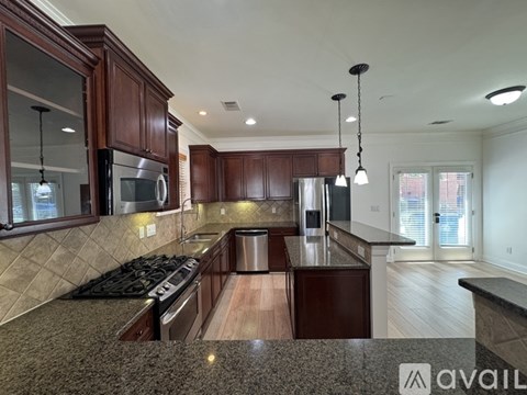A kitchen with dark wood cabinets and a granite countertop.
