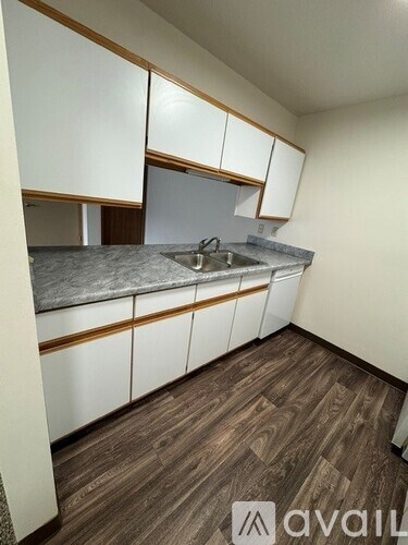 A kitchen with white cabinets and a wooden floor.