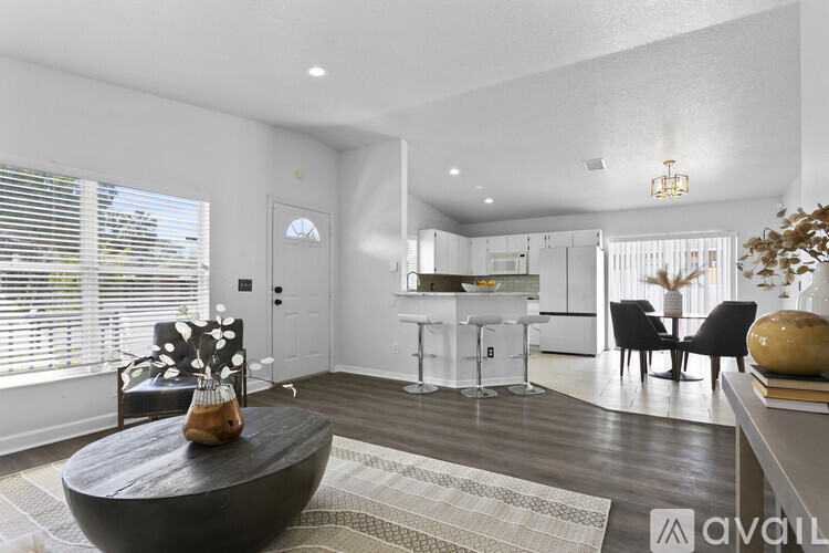 A modern living room with a black coffee table and a dining area in the background.