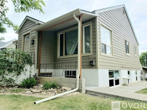 A house with a grey siding and a brown door is for sale.