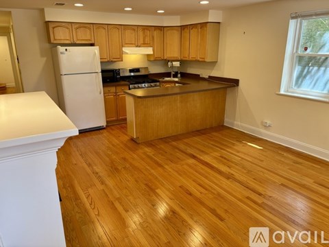A kitchen with wooden floors and a white refrigerator.