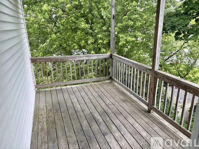 A wooden deck with a railing and trees in the background.