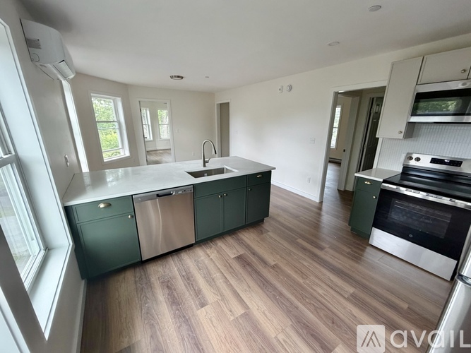 A kitchen with green cabinets and a wooden floor.
