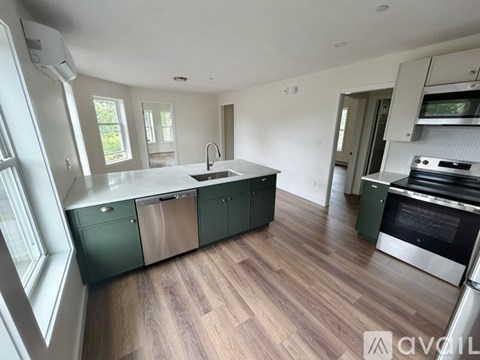 A kitchen with green cabinets and a wooden floor.