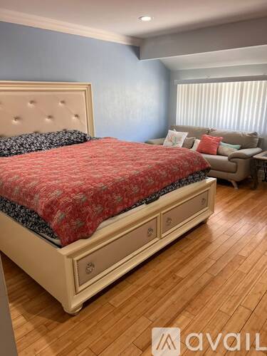 A bedroom with a large bed and a couch in the background.