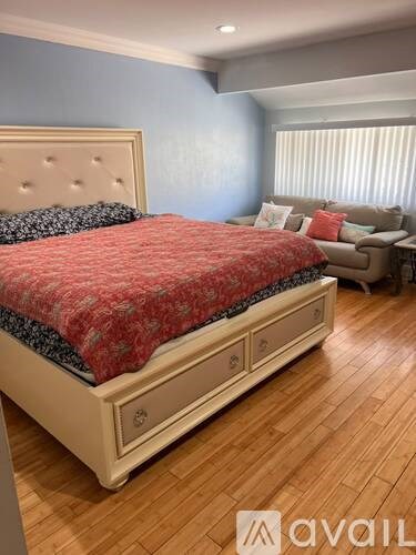 A bedroom with a large bed and a couch in the background.
