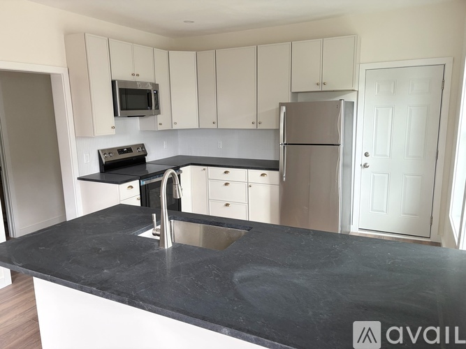 A kitchen with a black countertop and white cabinets.