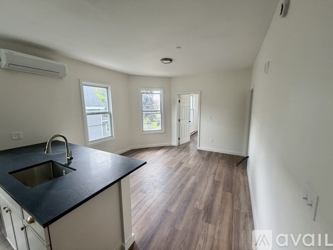 A kitchen with a black countertop and wooden flooring.