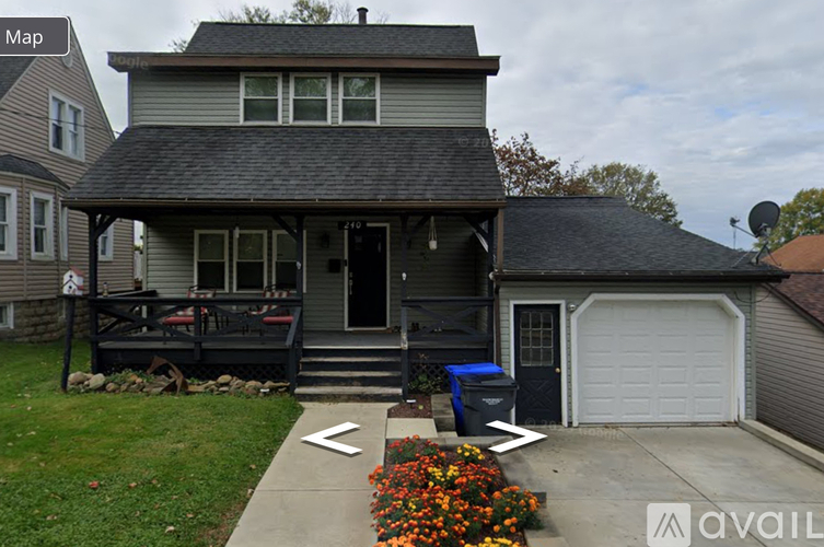 A house with a grey roof and a blue trash bin in front.