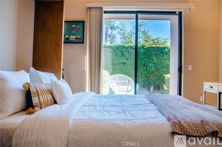 A bedroom with a large bed and a chair outside the window.