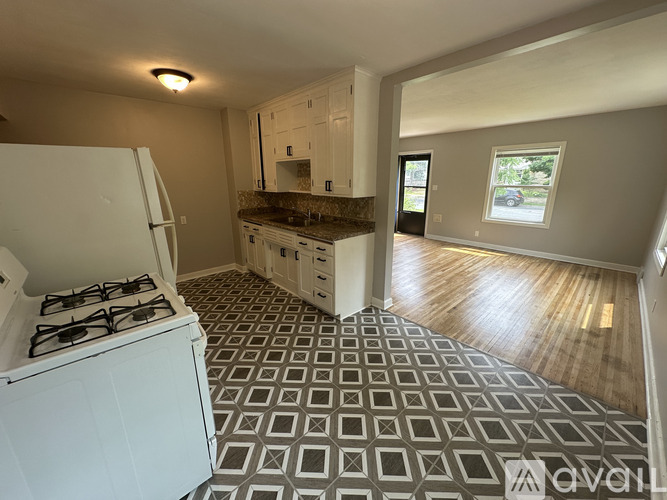 A kitchen with a white gas stove and a tiled floor.