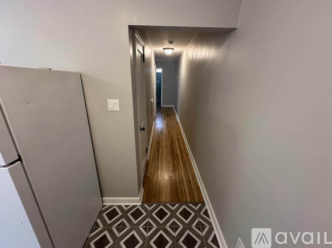 A hallway with a wooden floor and a metal door.
