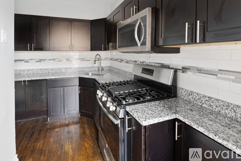 A kitchen with a black stove top oven and a black microwave above it.