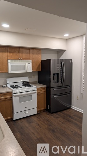 A kitchen with a white stove top oven and a black refrigerator.