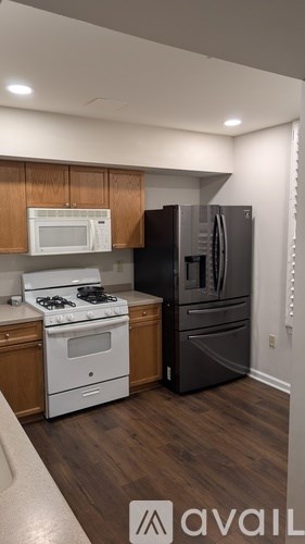A kitchen with a white stove top oven and a black refrigerator.