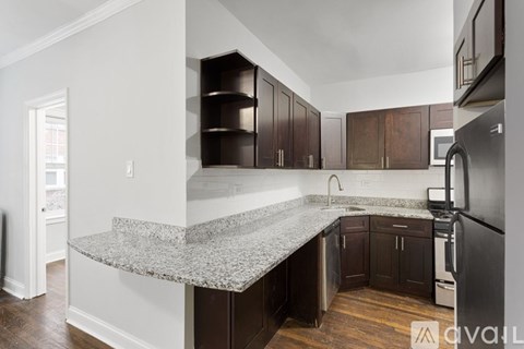 A kitchen with dark wood cabinets and a granite countertop.