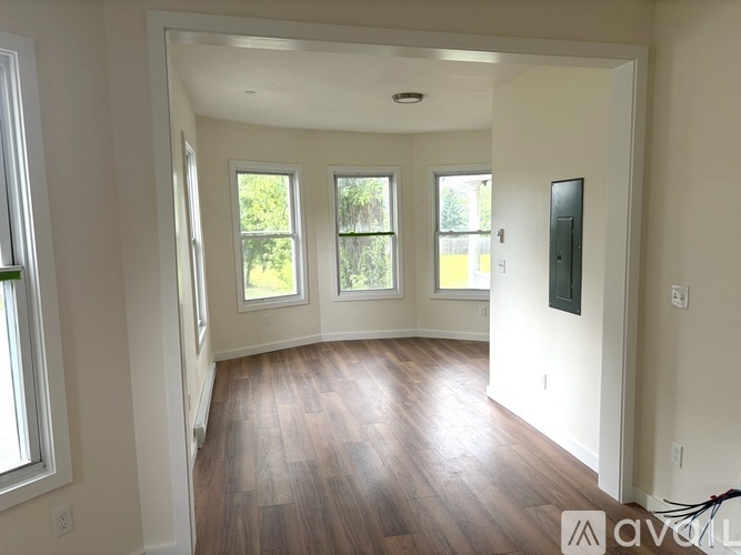 A room with wooden floors and three windows.