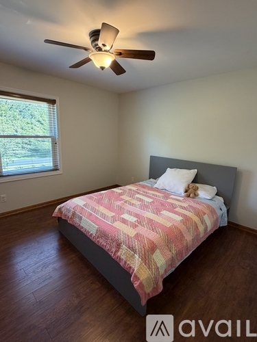 A bedroom with a bed, a ceiling fan, and a window.