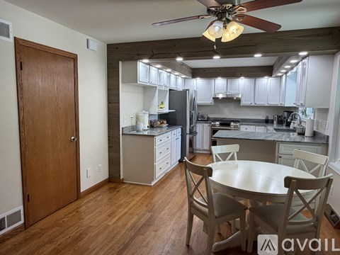 A kitchen with a table and chairs in the foreground and a refrigerator in the background.