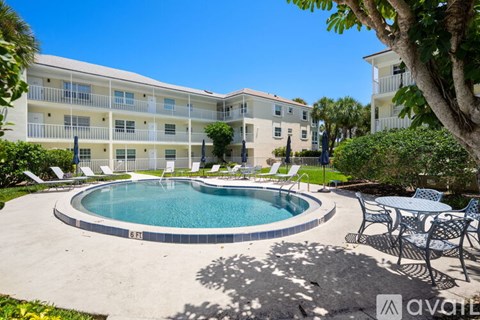 A pool surrounded by chairs and trees in front of a building.