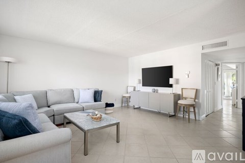 A living room with a grey couch, a coffee table, a television, and a chair.