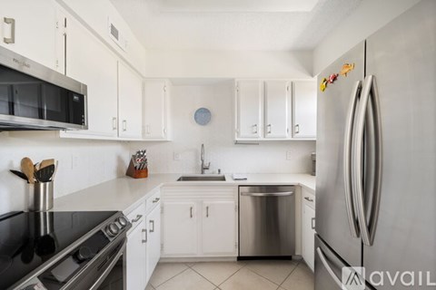 A kitchen with white cabinets and a stainless steel refrigerator.