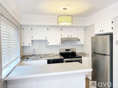 A kitchen with white cabinets and a stainless steel refrigerator.