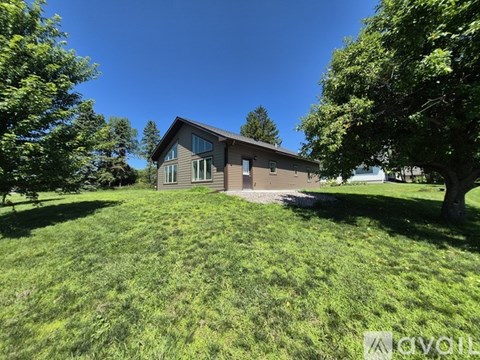 A house with a large lawn and trees in the background.