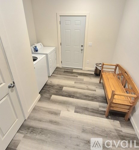 A small laundry room with a washer and dryer, a door, and a bench.