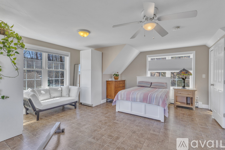 A bedroom with a bed, a couch, and a ceiling fan.