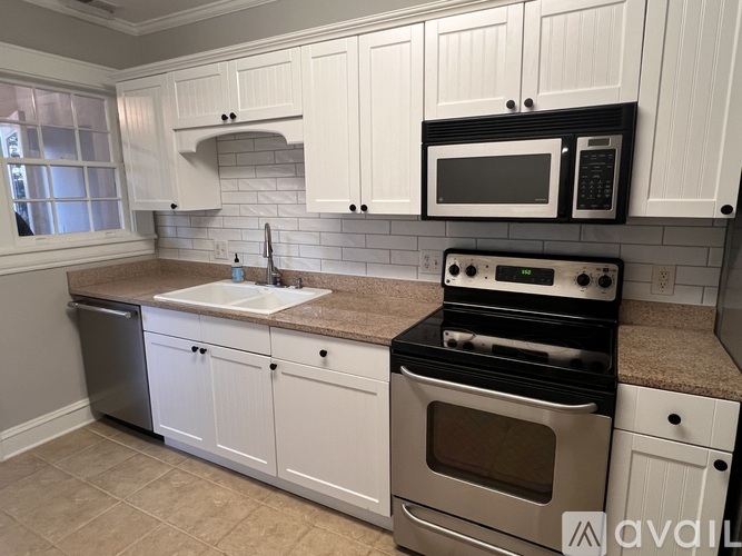 A kitchen with white cabinets and a black microwave above the stove.