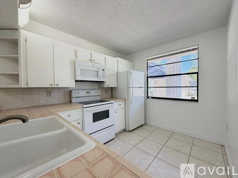 A kitchen with white appliances and a window.