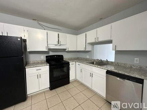 A kitchen with black appliances and white cabinets.