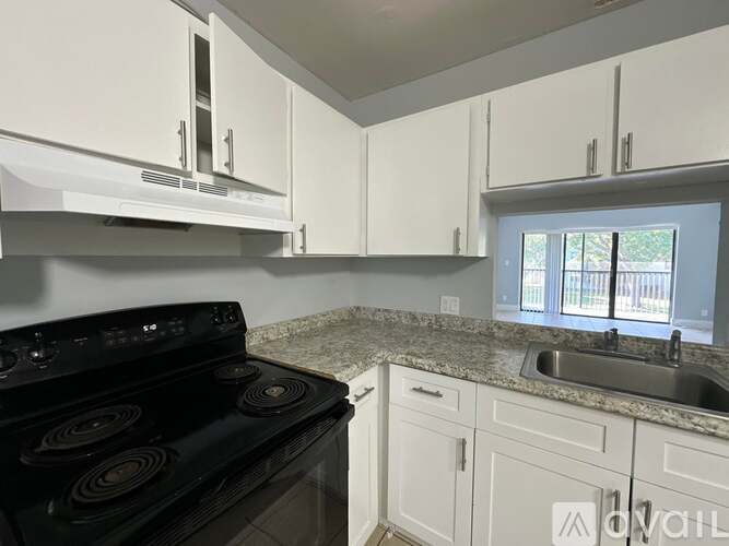 A kitchen with a black stove top oven and white cabinets.