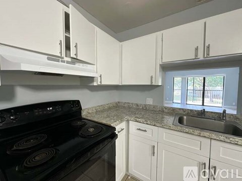 A kitchen with a black stove top oven and white cabinets.