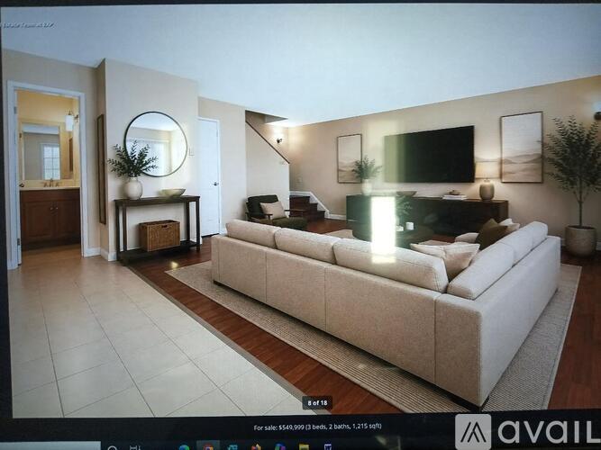 A living room with a large couch and a TV mounted on the wall.