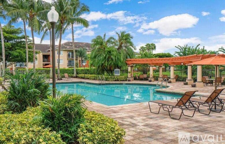 A pool surrounded by palm trees and lounge chairs.
