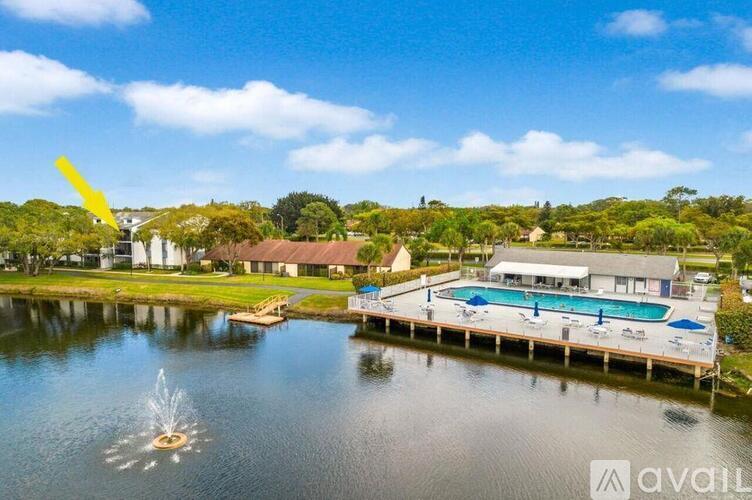 A large body of water with a fountain in the middle and a building with a pool in the background.