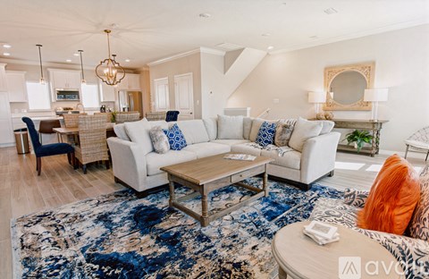 A living room with a white couch and a blue rug.
