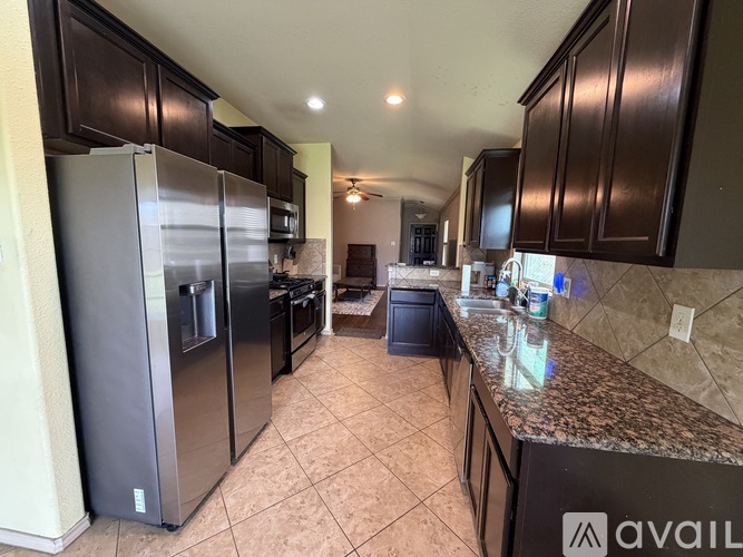 A kitchen with a refrigerator, oven, and sink.