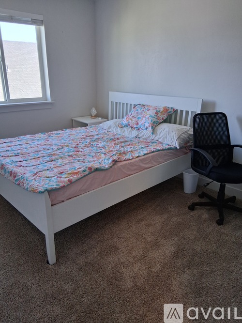 A bedroom with a bed, chair, and carpet.