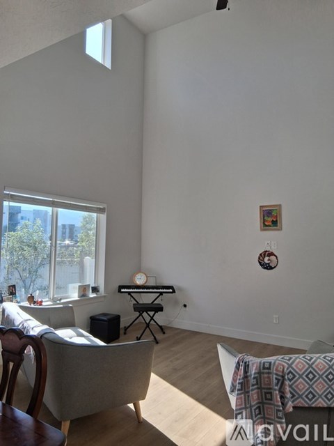 A living room with a grey couch and a piano.