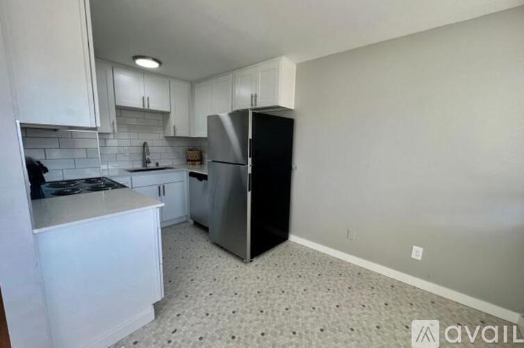 A kitchen with white cabinets and a black refrigerator.