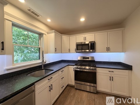 A kitchen with white cabinets and black countertops.