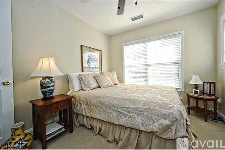 A bedroom with a bed, nightstand, and a table with a lamp on it.