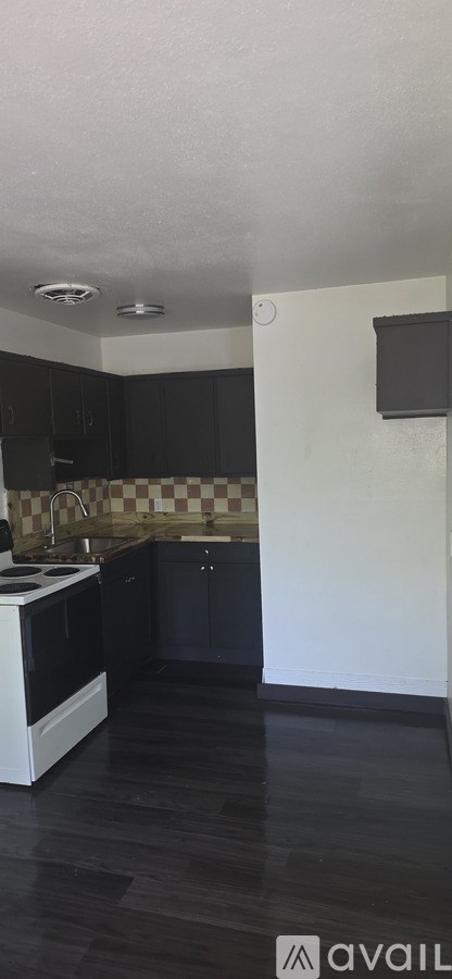 A kitchen with black cabinets and a checkered backsplash.