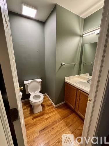 A bathroom with a toilet, sink, and mirror.